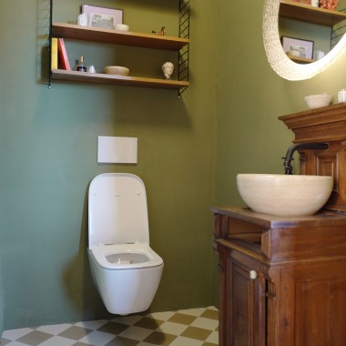 Gästebad in sanftem Grün: das Geberit Renova Plan WC kontrastiert die Waschkommode aus dunklem Holz.