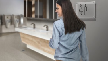 Dunkelhaarige junge Frau in einer öffentlichen Toilette